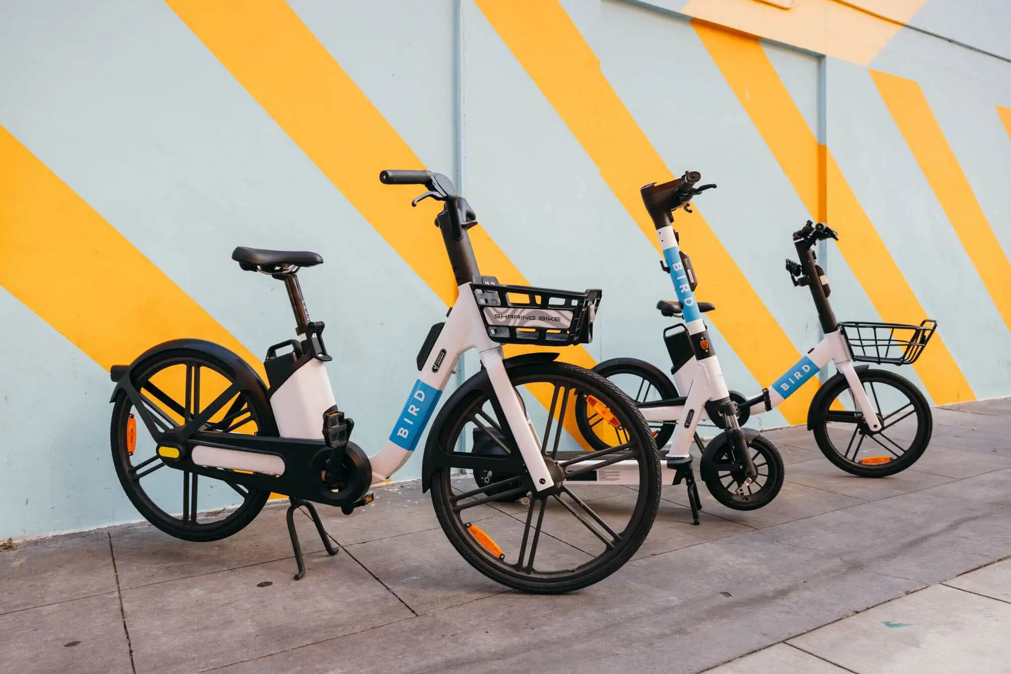 Bicicletas eléctricas Bird estacionadas frente a un colorido mural amarillo y turquesa