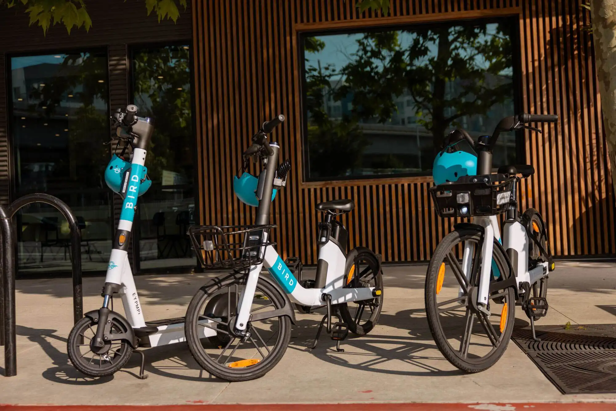 Bicicletas y patinetes eléctricos Bird estacionados frente a un edificio moderno